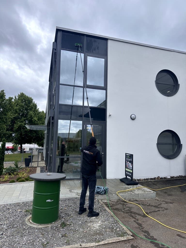 Fensterreinigung mit Reinwasser-Teleskopstange an Bürogebäude